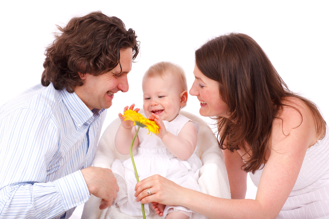 Happy parents and baby enjoy a flower